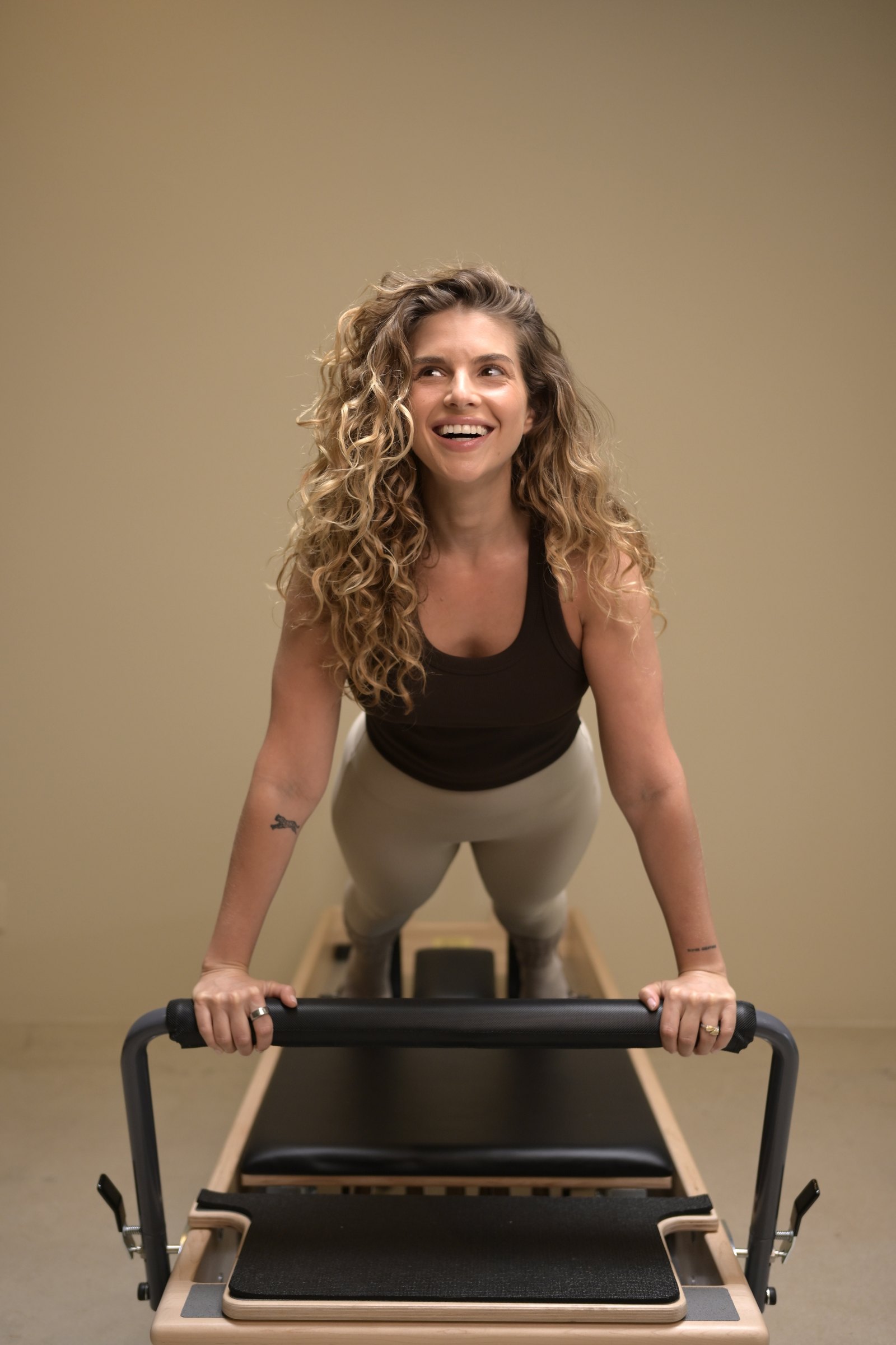 A student smiling while she holds a plank on the reformer