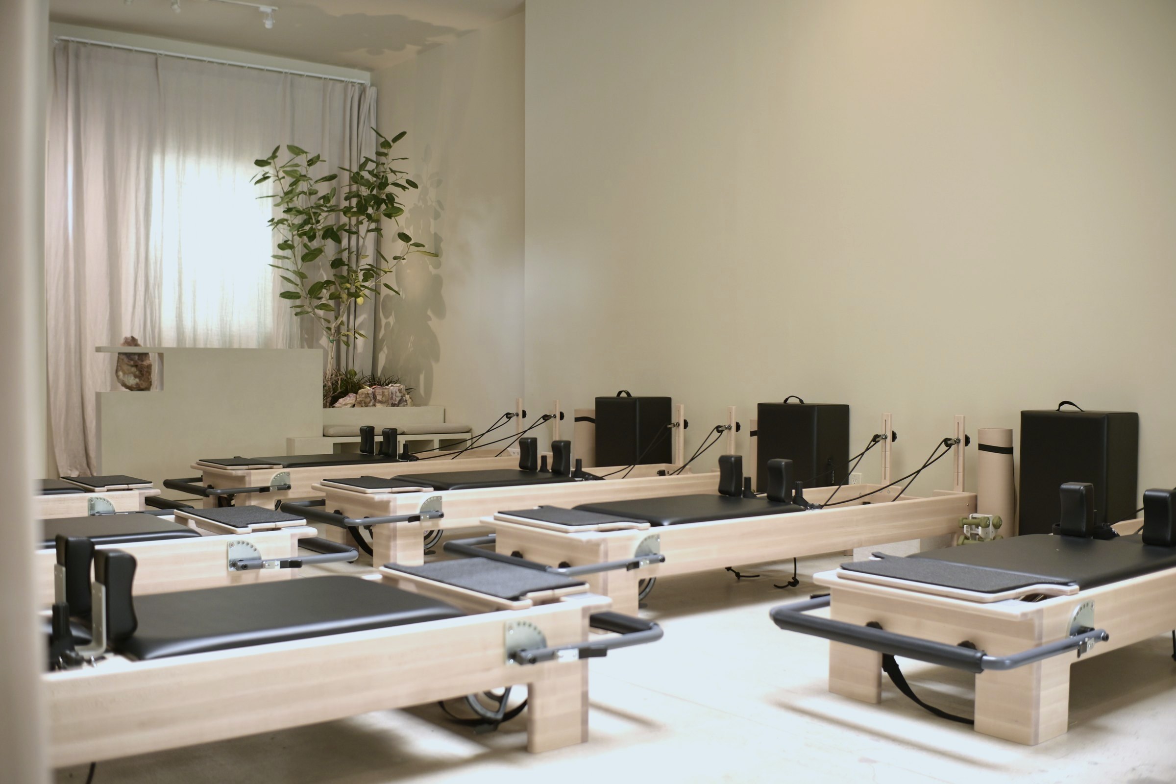 The reformer room with linen curtains and a plant by the window